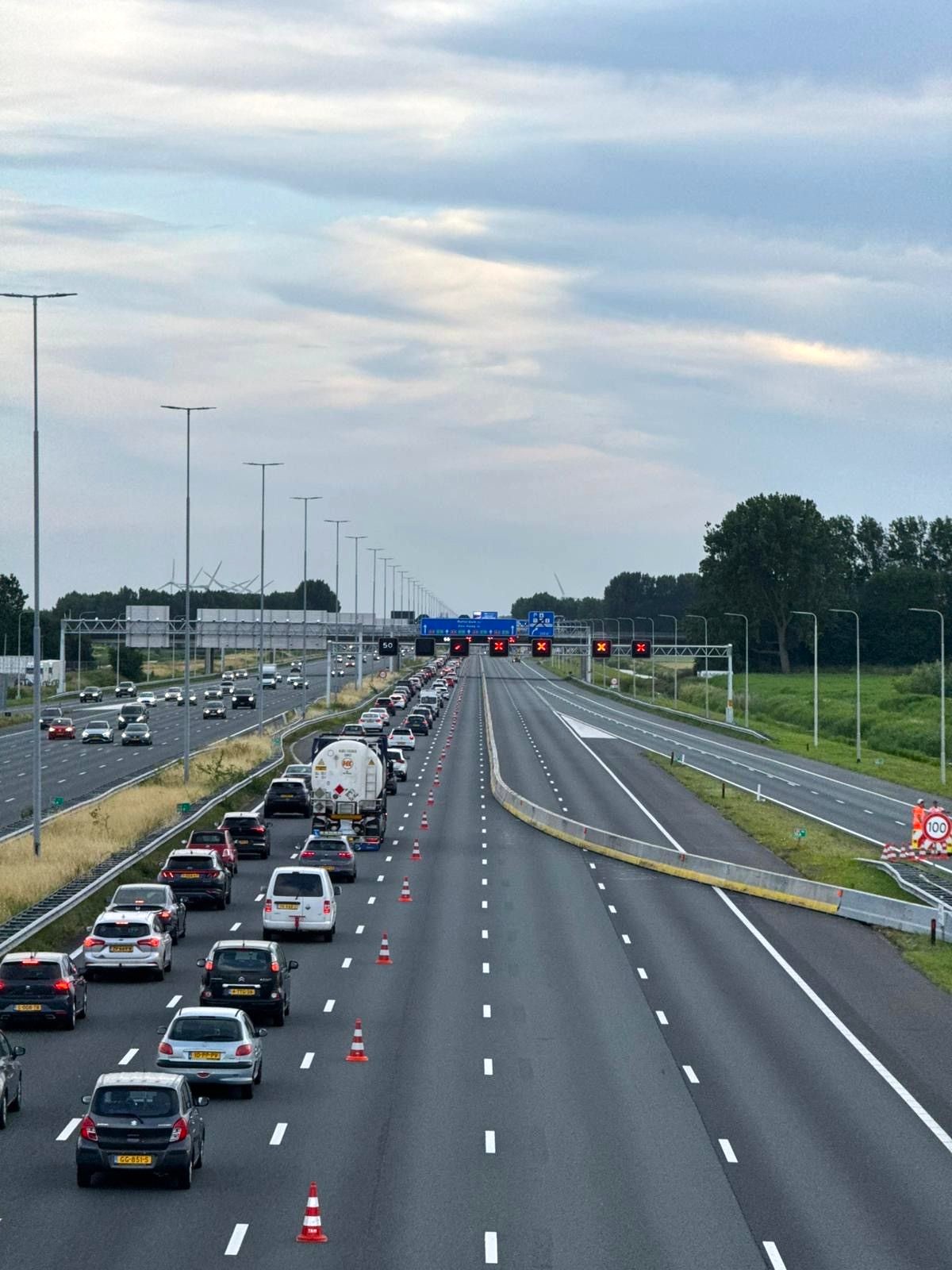 Een afgesloten snelweg met filevorming en verkeerskegels die het verkeer begeleiden.